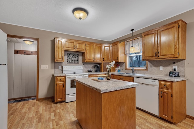 kitchen with a sink, light wood finished floors, white appliances, light countertops, and decorative backsplash