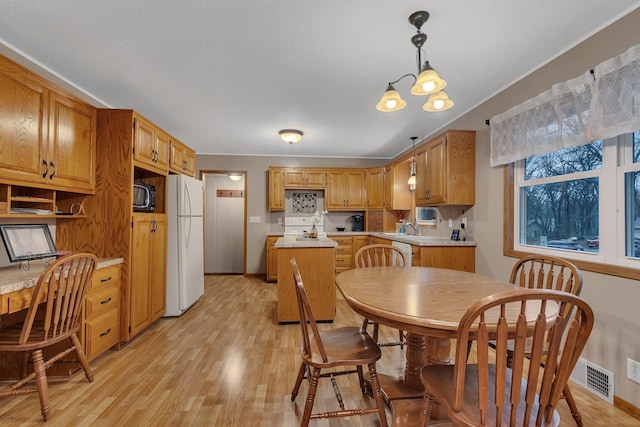 dining room featuring baseboards, light wood-style flooring, and visible vents