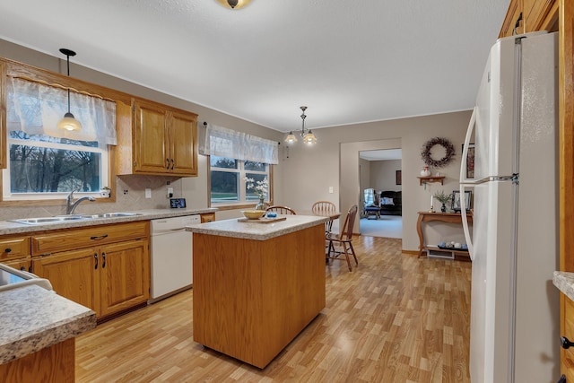 kitchen featuring backsplash, a sink, light countertops, light wood-style floors, and white appliances