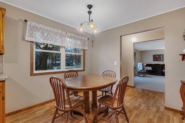 dining room with crown molding, baseboards, light wood finished floors, and a chandelier