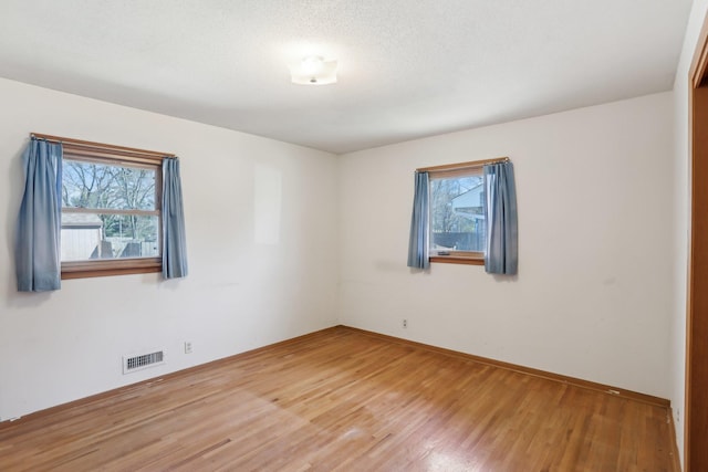 unfurnished room with light wood-style floors, a healthy amount of sunlight, baseboards, and visible vents