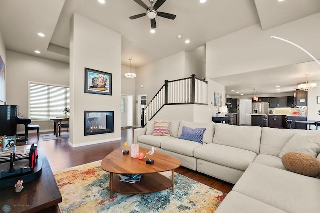 living area featuring baseboards, wood finished floors, ceiling fan with notable chandelier, and recessed lighting