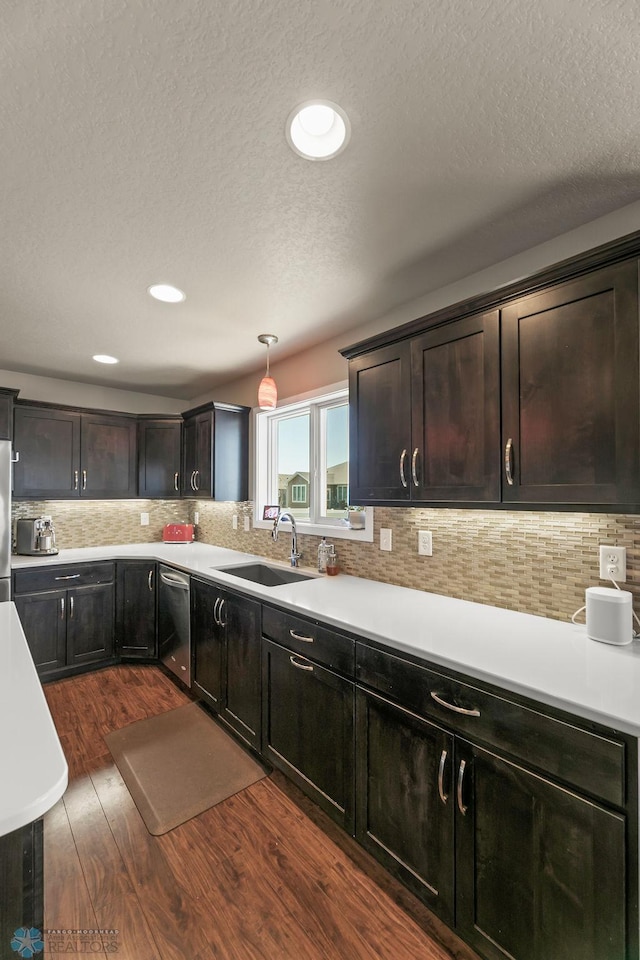 kitchen featuring a sink, stainless steel appliances, dark wood finished floors, a textured ceiling, and light countertops