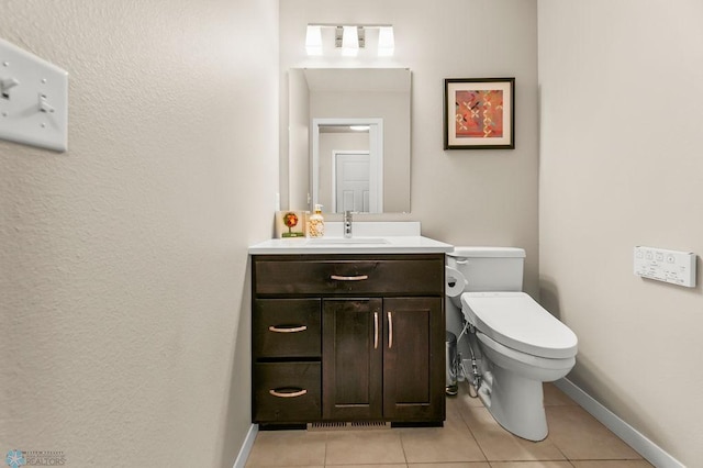 half bathroom featuring baseboards, tile patterned floors, vanity, and toilet