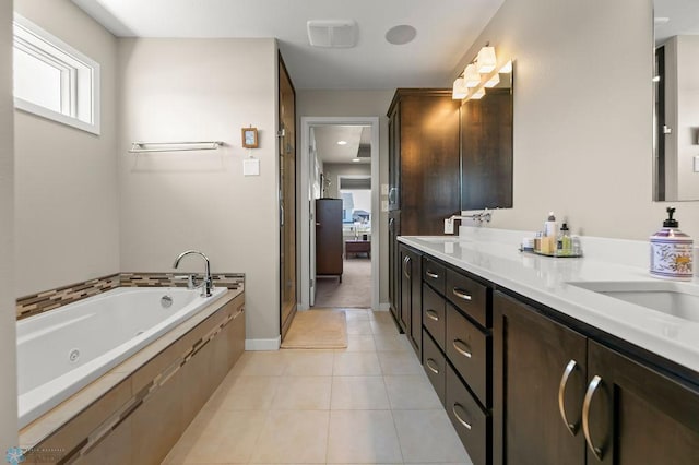 bathroom with double vanity, a jetted tub, a sink, tile patterned floors, and baseboards