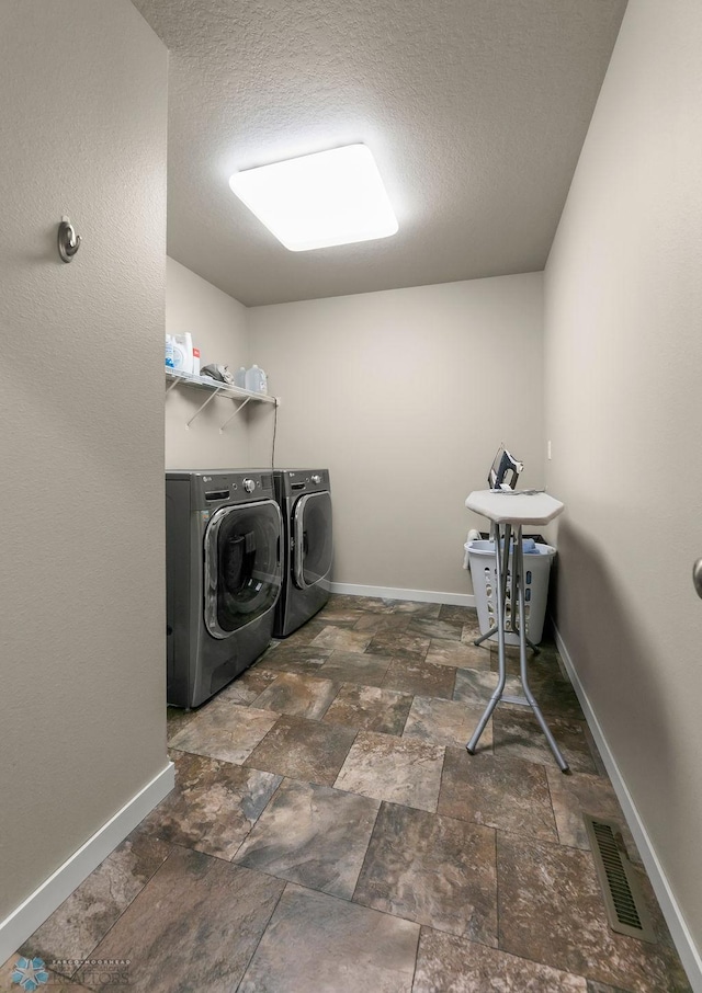 washroom featuring independent washer and dryer, stone finish floor, baseboards, visible vents, and laundry area