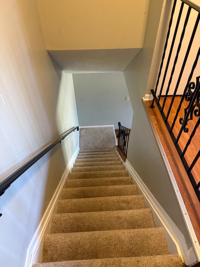 staircase featuring baseboards and carpet
