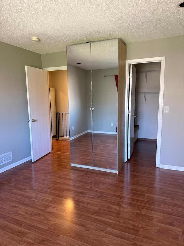 unfurnished bedroom with a textured ceiling, visible vents, and baseboards