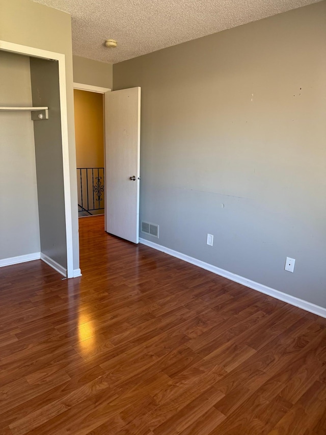 unfurnished bedroom with baseboards, wood finished floors, a textured ceiling, and visible vents