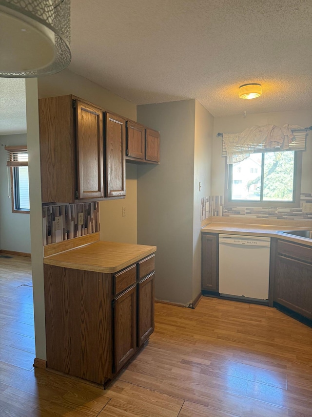 kitchen with light countertops, light wood-type flooring, a textured ceiling, and dishwasher