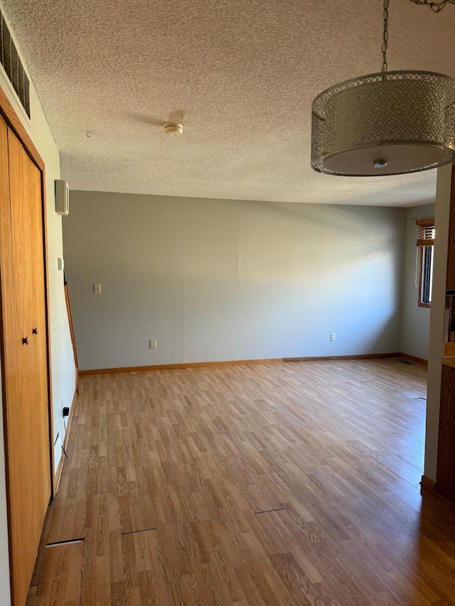 interior space featuring visible vents, baseboards, a textured ceiling, and wood finished floors