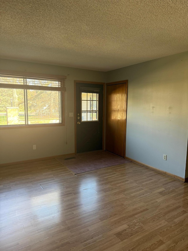 interior space with baseboards, a textured ceiling, and wood finished floors