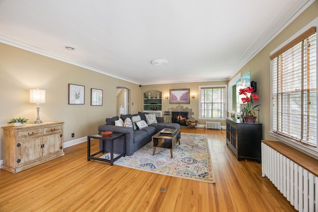 4904 11th Ave S, Minneapolis, MN 55417 - living room featuring radiator heating unit, light wood-style flooring, arched walkways, crown molding, and a warm lit fireplace