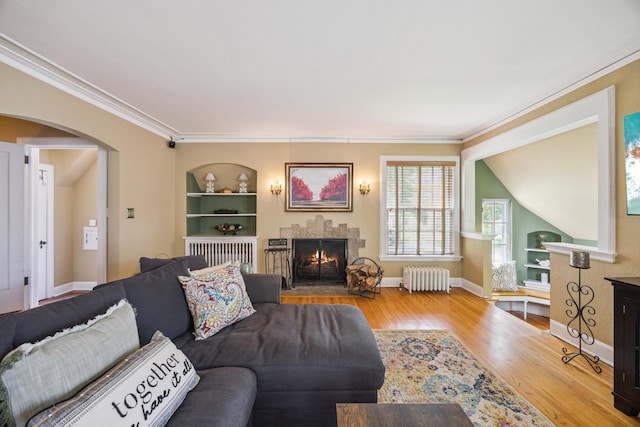 4904 11th Ave S, Minneapolis, MN 55417 - living room with radiator heating unit, arched walkways, wood finished floors, a warm lit fireplace, and crown molding