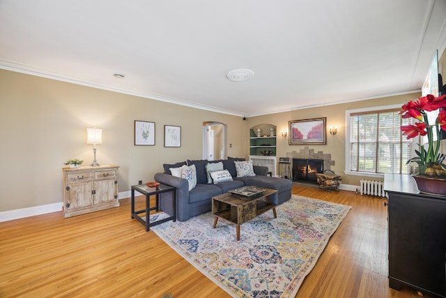 4904 11th Ave S, Minneapolis, MN 55417 - living room with radiator, arched walkways, crown molding, a lit fireplace, and light wood-style flooring