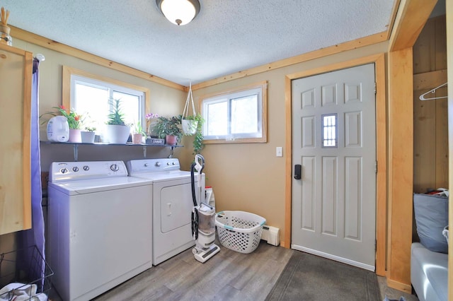 washroom with laundry area, a textured ceiling, wood finished floors, a baseboard heating unit, and washing machine and dryer