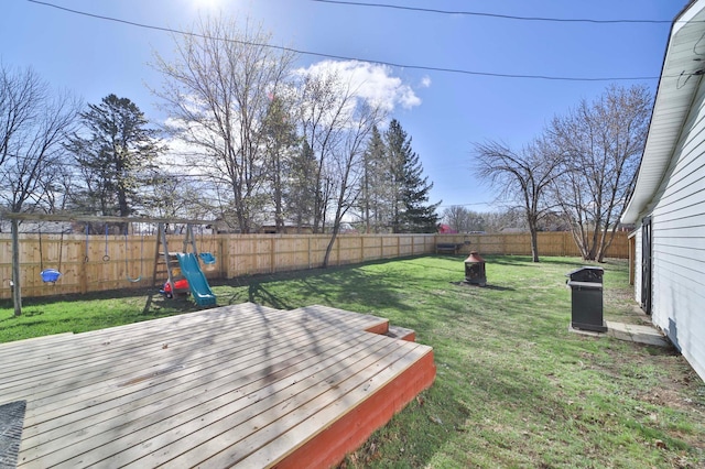 view of yard with a deck, a fenced backyard, and a playground