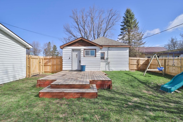 back of property with a fenced backyard, a playground, a yard, and a deck
