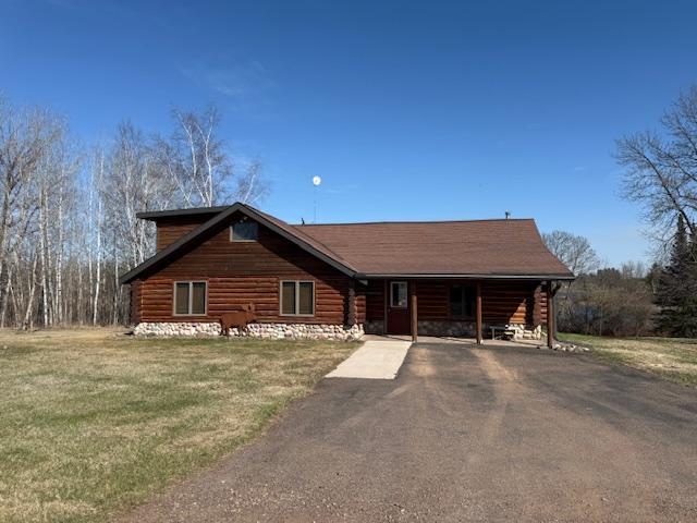 log-style house with aphalt driveway and a front lawn