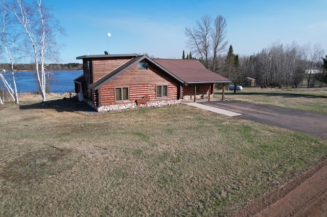 view of front of property with driveway, a water view, and a front lawn