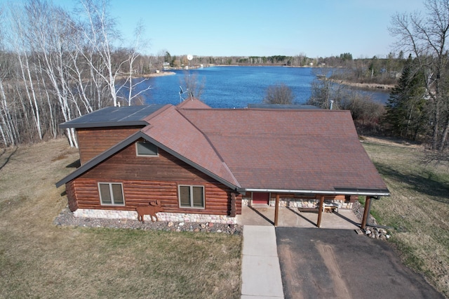 view of front of property featuring aphalt driveway, a water view, a front lawn, and an attached carport