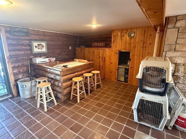bar featuring a wood stove, tile patterned flooring, a dry bar, and wood walls