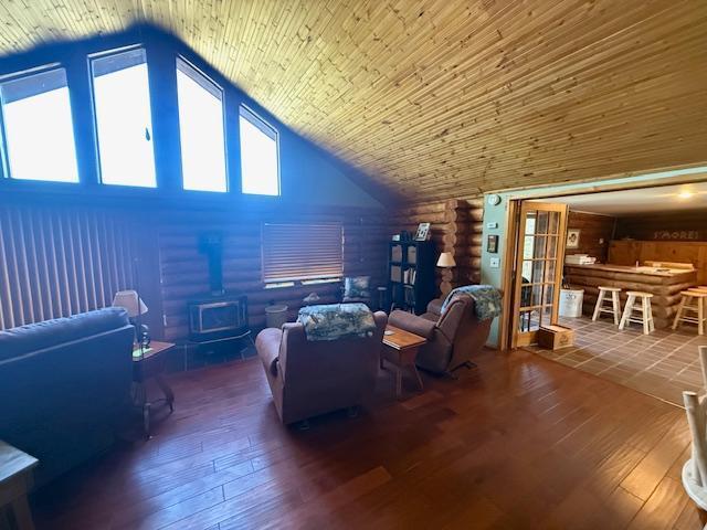 living area with a wood stove, high vaulted ceiling, and hardwood / wood-style flooring