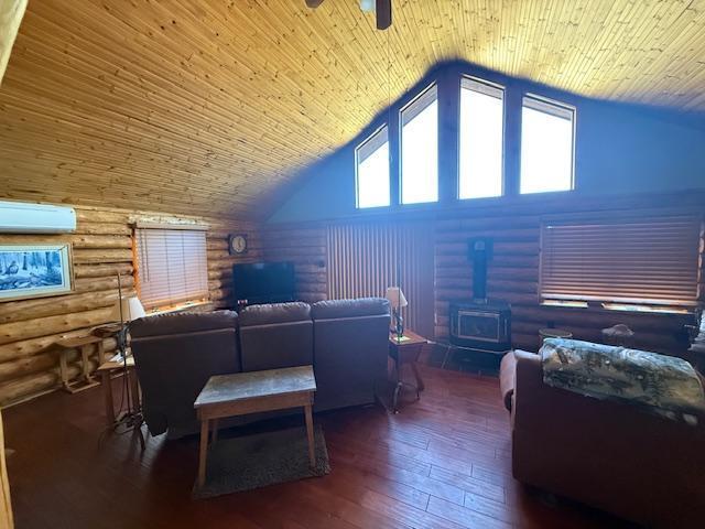 living area with hardwood / wood-style flooring, a wood stove, log walls, an AC wall unit, and a ceiling fan