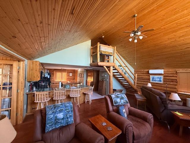 living area with wood ceiling, log walls, a ceiling fan, high vaulted ceiling, and stairs