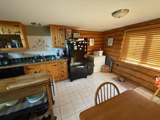 kitchen with a sink, black appliances, rustic walls, and tile countertops