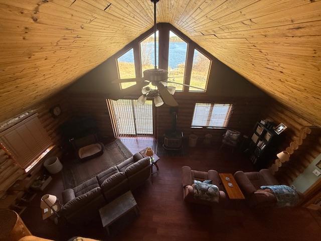 living area featuring a wood stove, wooden ceiling, vaulted ceiling, and wood finished floors