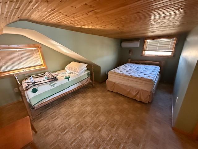 bedroom with wood ceiling, a wall mounted AC, and vaulted ceiling