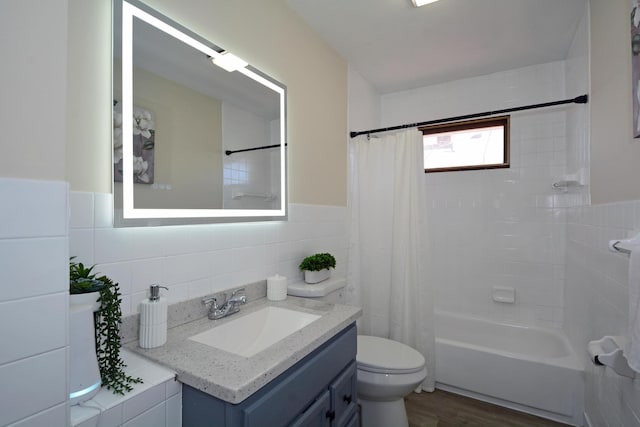 bathroom with tile walls, wood finished floors, vanity, toilet, and shower / bath combo with shower curtain