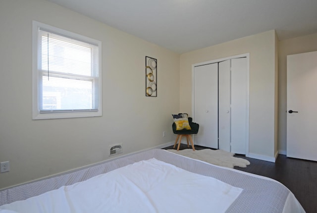 bedroom with baseboards, dark wood-type flooring, and a closet