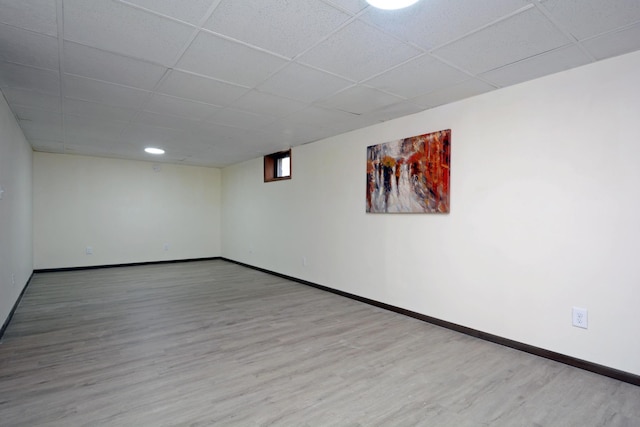 finished basement with baseboards, wood finished floors, and a paneled ceiling