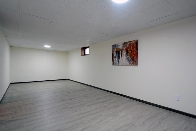 spare room with baseboards, a drop ceiling, and wood finished floors
