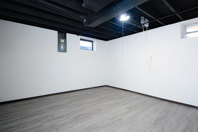 basement featuring plenty of natural light, baseboards, wood finished floors, and electric panel