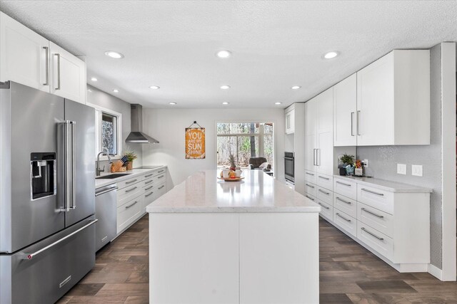 1206 Pinecrest Ln, New Richmond, WI 54017 - kitchen with appliances with stainless steel finishes, wall chimney exhaust hood, a sink, a kitchen island, and light stone countertops