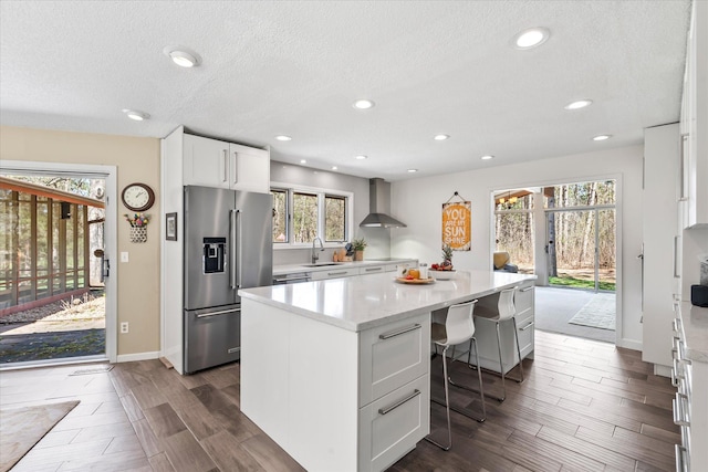 1206 Pinecrest Ln, New Richmond, WI 54017 - kitchen featuring high end refrigerator, wall chimney exhaust hood, a sink, a kitchen island, and wood finish floors