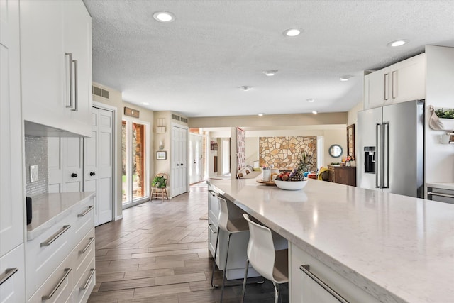 1206 Pinecrest Ln, New Richmond, WI 54017 - kitchen featuring high quality fridge, a textured ceiling, white cabinetry, wood finished floors, and light stone counters