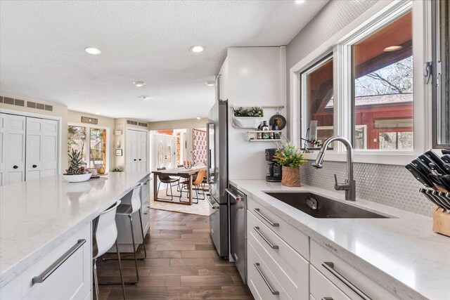 1206 Pinecrest Ln, New Richmond, WI 54017 - kitchen featuring a sink, dark wood-style floors, white cabinets, tasteful backsplash, and stainless steel appliances