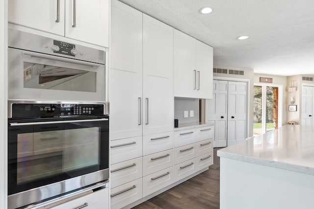 1206 Pinecrest Ln, New Richmond, WI 54017 - kitchen featuring a textured ceiling, double oven, light stone countertops, white cabinets, and dark wood-type flooring