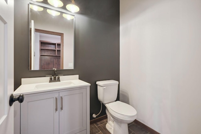 bathroom with baseboards, toilet, and vanity