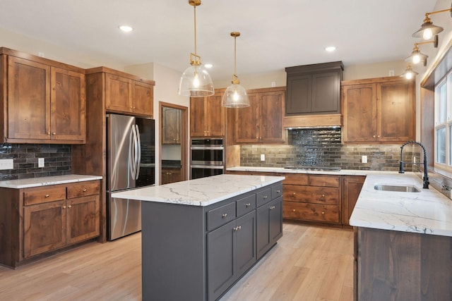 kitchen with a center island, a sink, appliances with stainless steel finishes, and light wood-type flooring