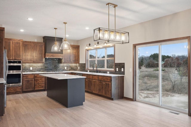 kitchen with tasteful backsplash, stainless steel double oven, plenty of natural light, light countertops, and visible vents