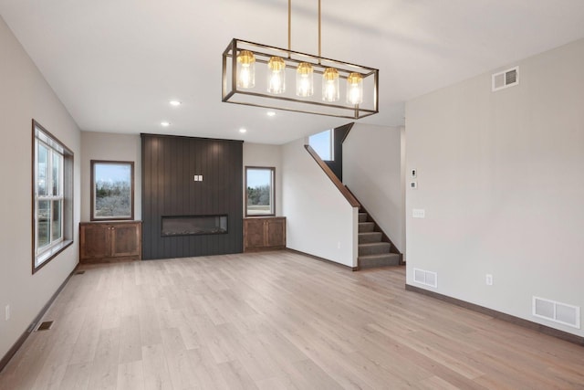 unfurnished living room with light wood finished floors, visible vents, and a wealth of natural light
