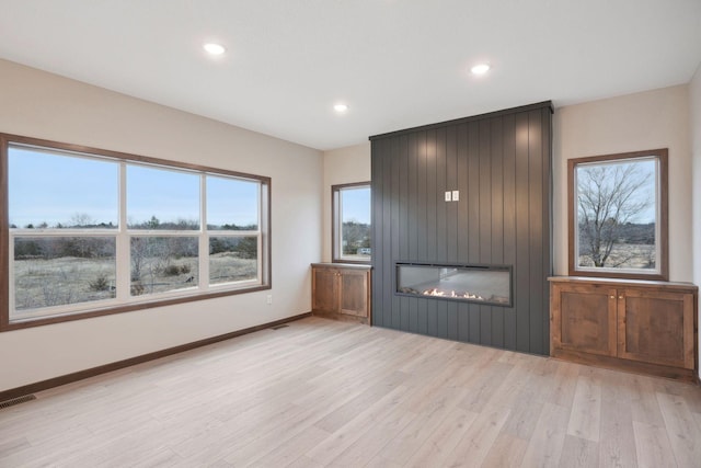 unfurnished living room featuring recessed lighting, a large fireplace, light wood-style floors, visible vents, and baseboards