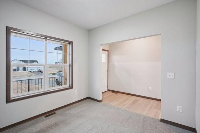 unfurnished room with baseboards, visible vents, and light colored carpet