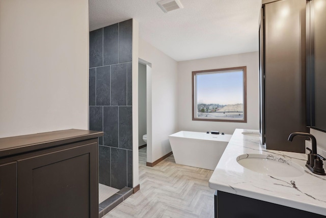 full bath featuring a sink, tiled shower, double vanity, a freestanding bath, and visible vents