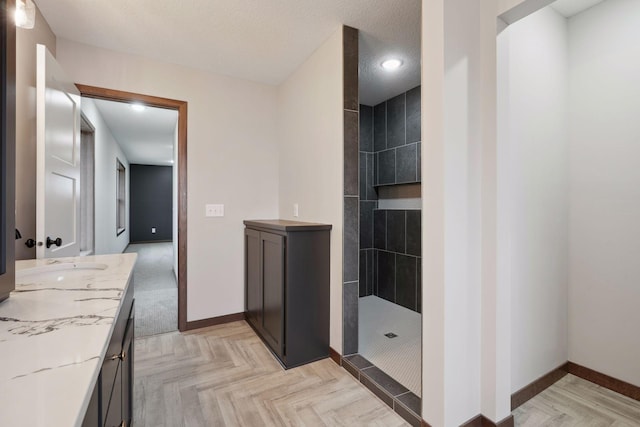 full bathroom with baseboards, recessed lighting, a walk in shower, and vanity